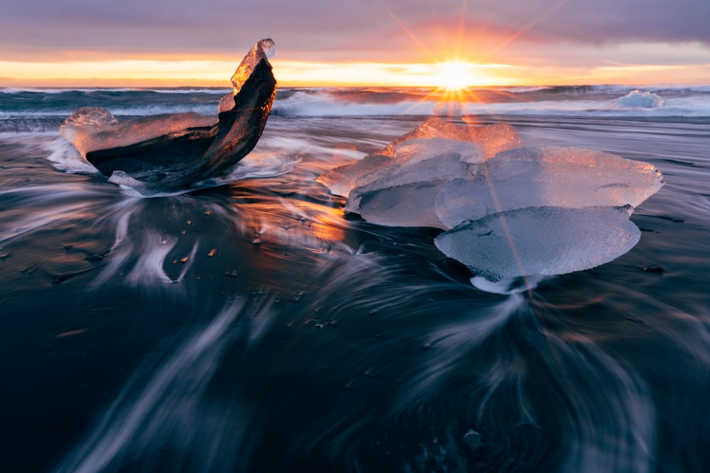 Roca marrón en el cuerpo de agua durante la puesta del sol