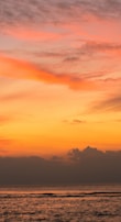 A sunset photo with vibrant orange and pink hues over the sea.