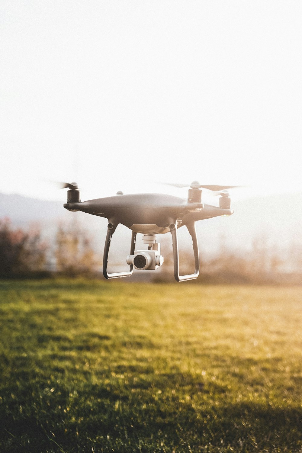 white drone flying over green grass field during daytime