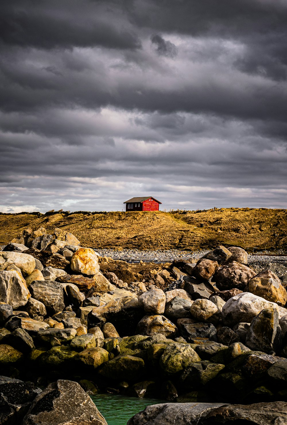 red and white house on brown field under cloudy sky