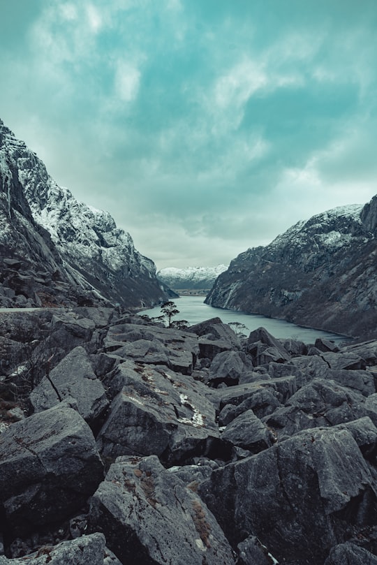 rocky mountain near body of water during daytime in Magma Geopark Norway