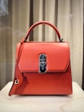 red leather handbag on white table