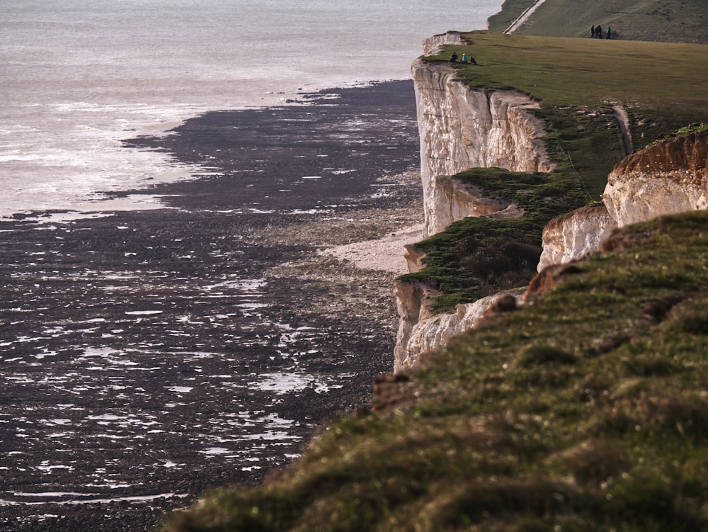 brown and green cliff beside body of water during daytime