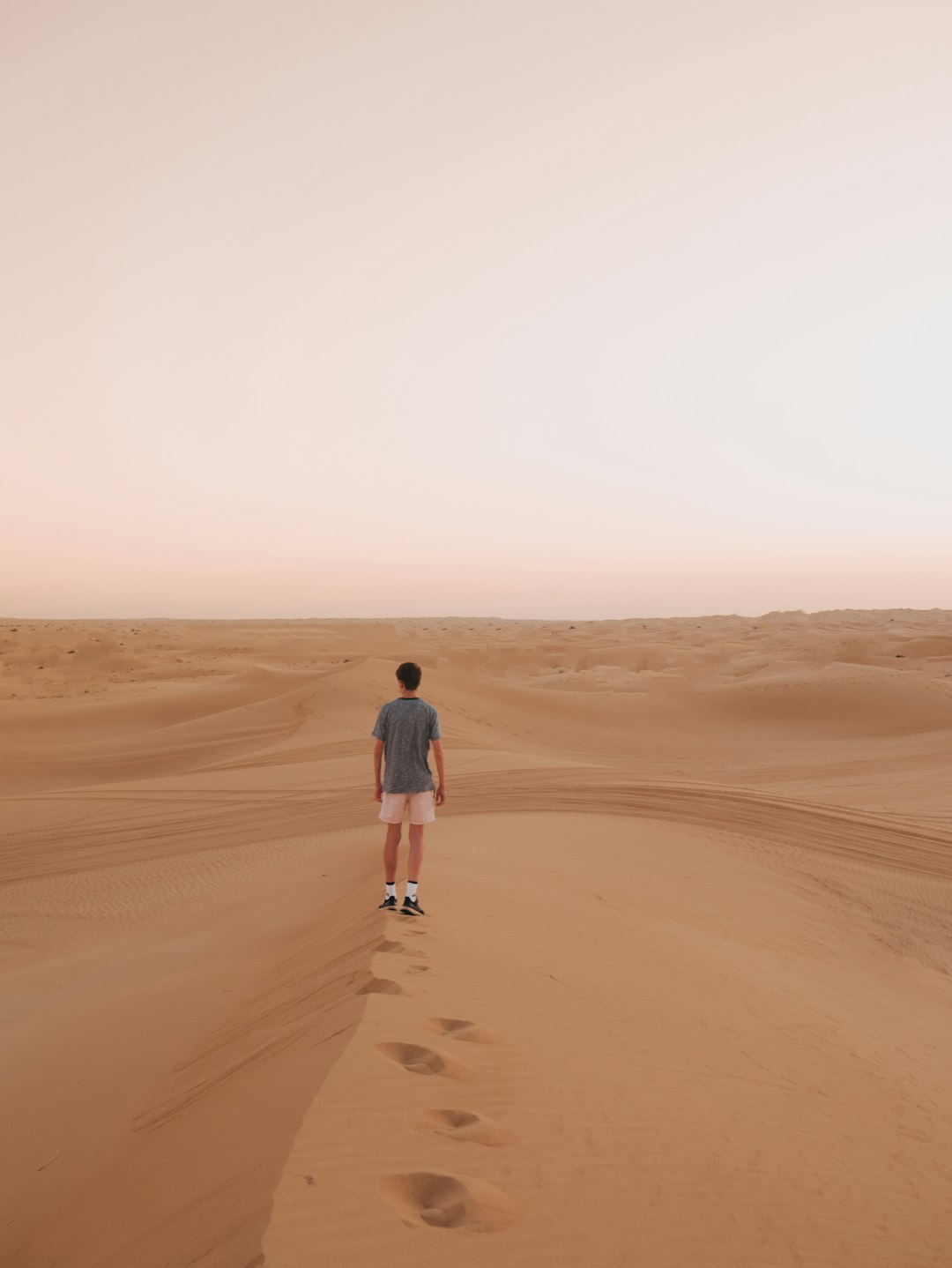 woman in black jacket walking on brown sand during daytime