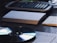 A wooden desk holds a calculator, stacks of paper, and a CD. Papers are organized and placed across the surface, while the CD reflects light with its iridescent surface.