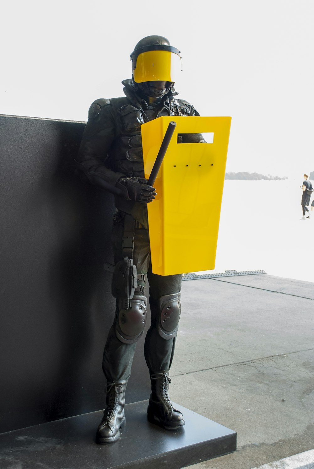 man in black jacket and yellow pants wearing black helmet holding yellow umbrella