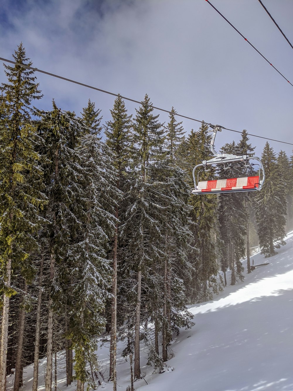 red cable car over snow covered pine trees under blue sky during daytime