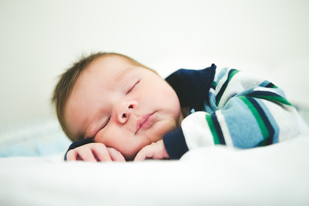 bébé en chemise rayée noire et blanche couché sur le lit