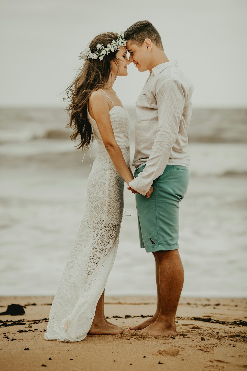 man and woman standing on beach during daytime