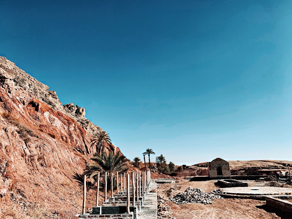 white wooden fence on brown rocky mountain under blue sky during daytime