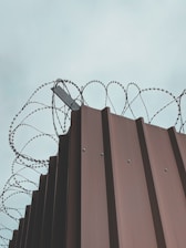 A sturdy security fence with barbed wire atop, installed around a government building.