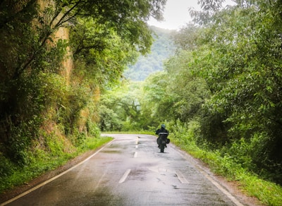A biker navigating a winding road through the lush Amazon rainforest.