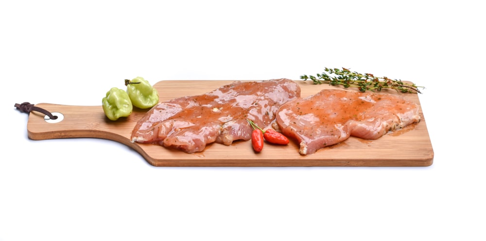 raw meat with green vegetable on brown wooden chopping board