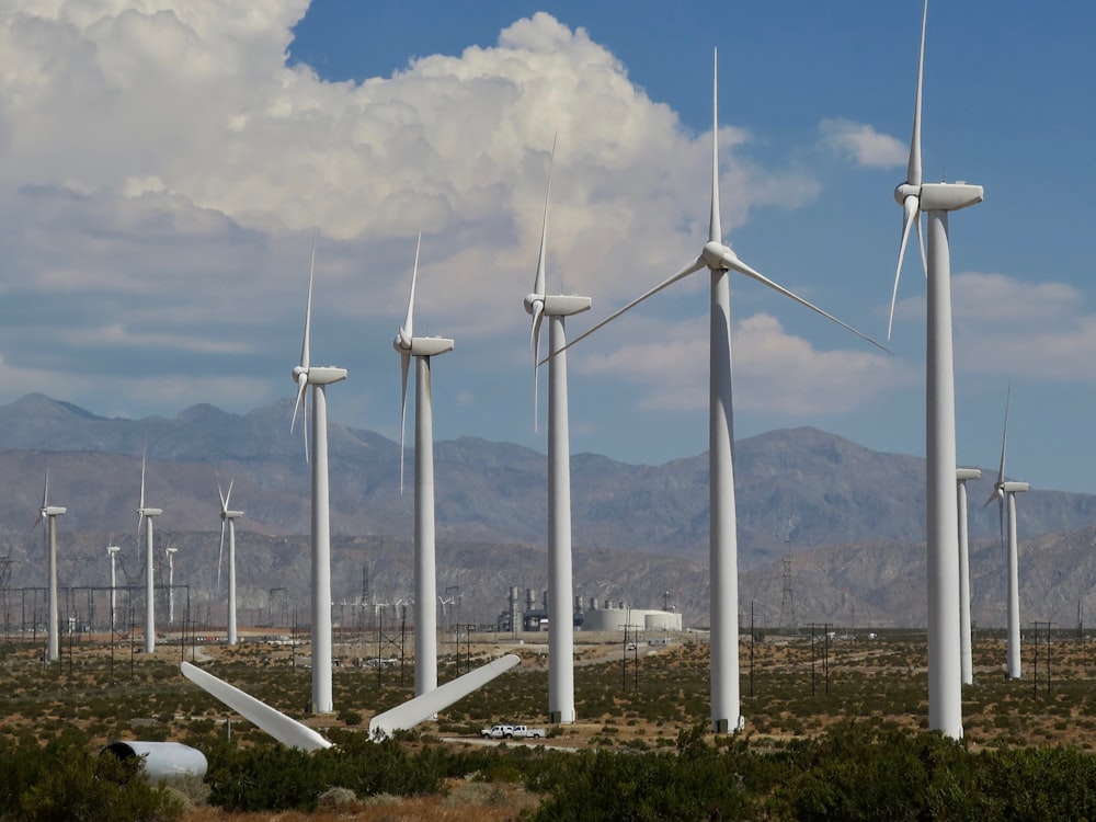 white wind turbines on brown field under white clouds and blue sky during daytime