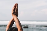 Two hands are positioned in a prayer pose with a blurred ocean background, conveying a sense of calm and reflection.