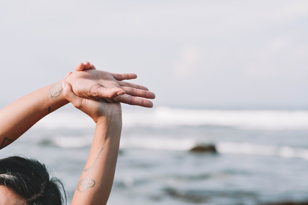 mujer sosteniendo sus manos en la playa durante el día