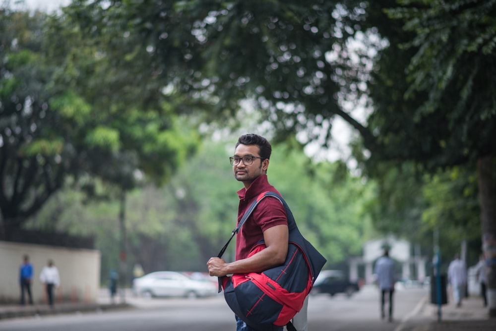 man in black and red polo shirt holding black smartphone