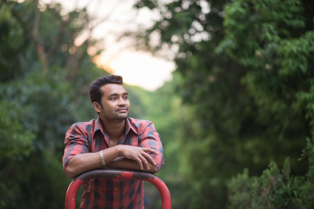 man in red and white plaid dress shirt sitting on red plastic chair