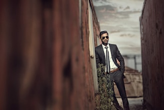 man in black suit standing on brown wooden bridge during daytime