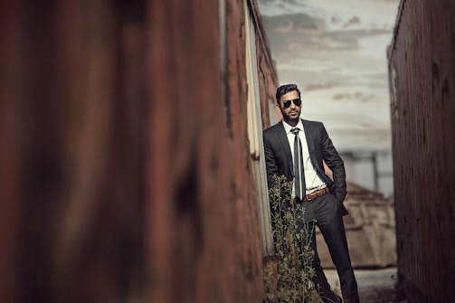 man in black suit standing on brown wooden bridge during daytime