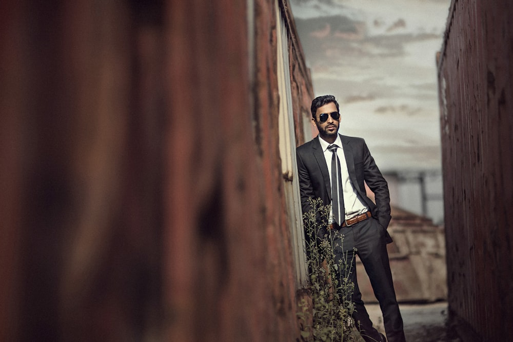 man in black suit standing on brown wooden bridge during daytime