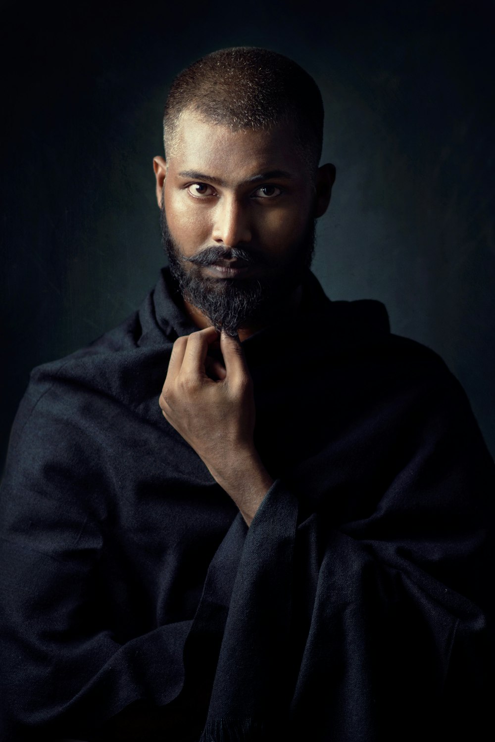 man in black hoodie holding his chin