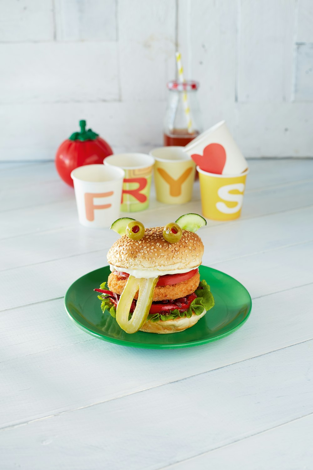 burger on green plate beside red and white polka dot cups