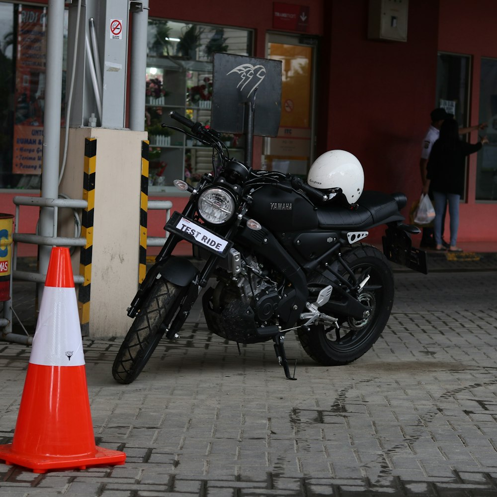 black motorcycle parked beside red traffic cone