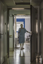 A nurse accompanying a patient through a hospital corridor with reassuring presence.