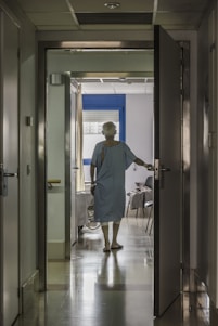 A warm, welcoming nurse assisting a patient in a bright, modern hospital corridor filled with natural light.