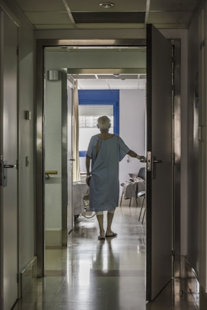 man in blue scrub suit standing near brown wooden door