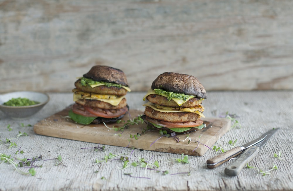 a couple of sandwiches sitting on top of a cutting board