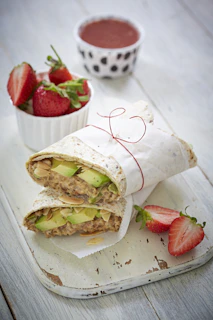 sliced bread with cheese and strawberries on white paper towel