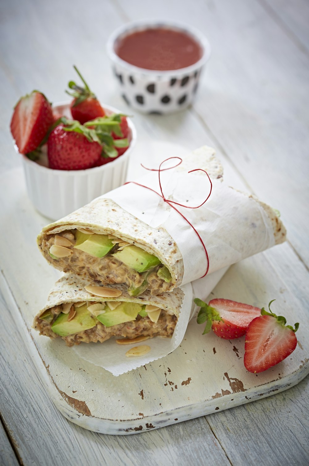 sliced bread with cheese and strawberries on white paper towel