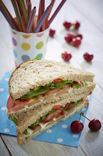 Colorful lunchbox filled with fresh fruits, veggies, and a sandwich.