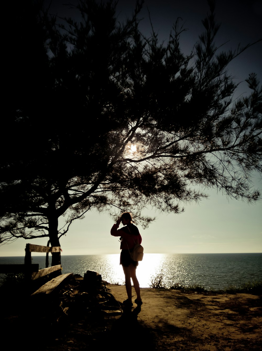 woman in black tank top and white shorts standing on rock near body of water during