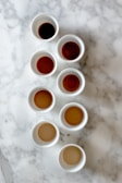 An array of colorful coffee cups on a textured black surface.