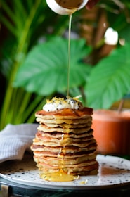A vibrant plate of mino hotcakes topped with fresh berries and a drizzle of honey, glowing under soft natural light.