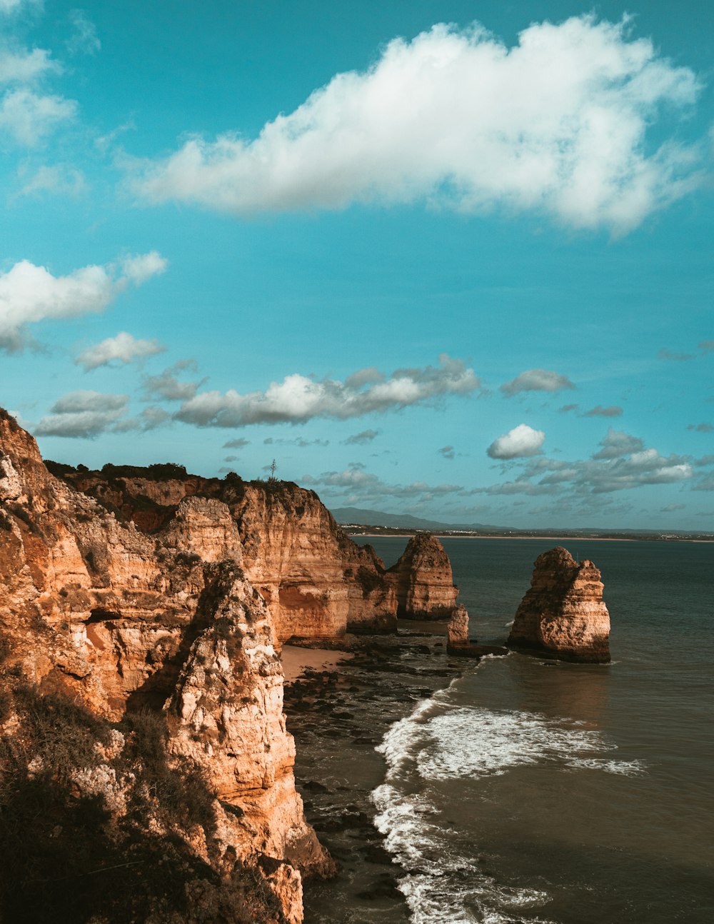 brown rock formation on sea under blue sky during daytime