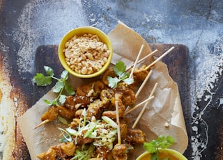 a plate of food with skewers and dipping sauce