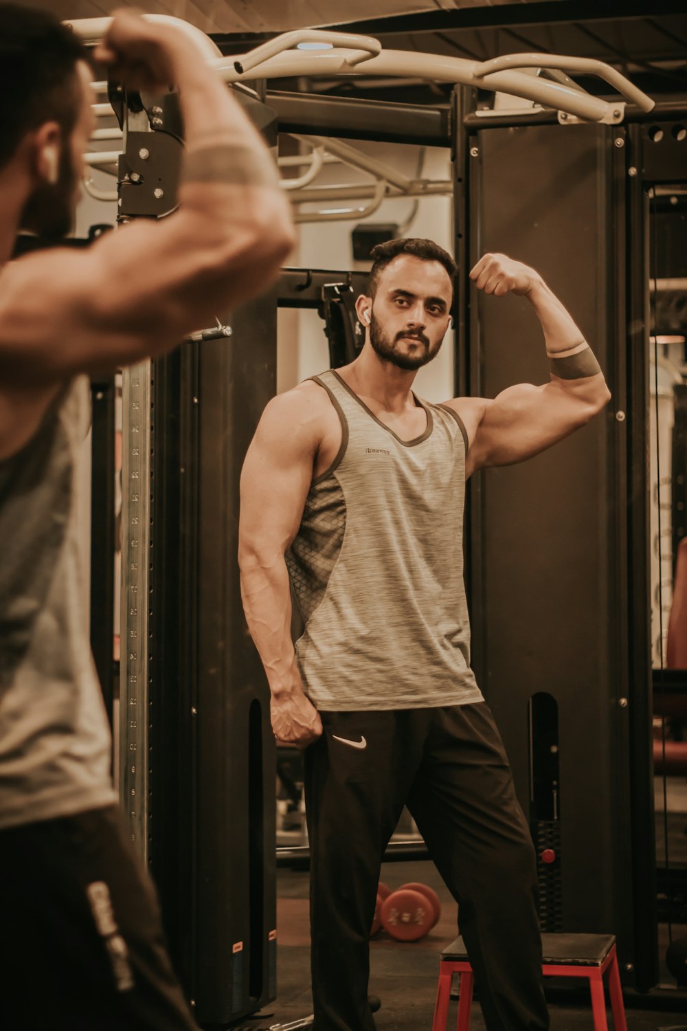 man in gray tank top and black pants standing near black wooden door