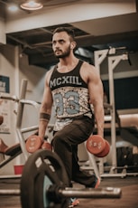 man in black and white tank top and brown shorts sitting on black and red exercise
