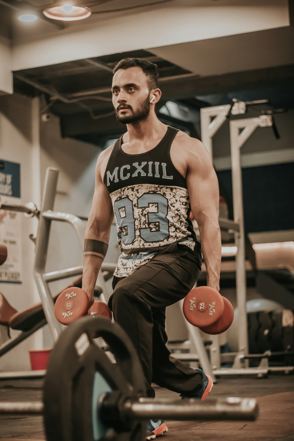 man in black and white tank top and brown shorts sitting on black and red exercise