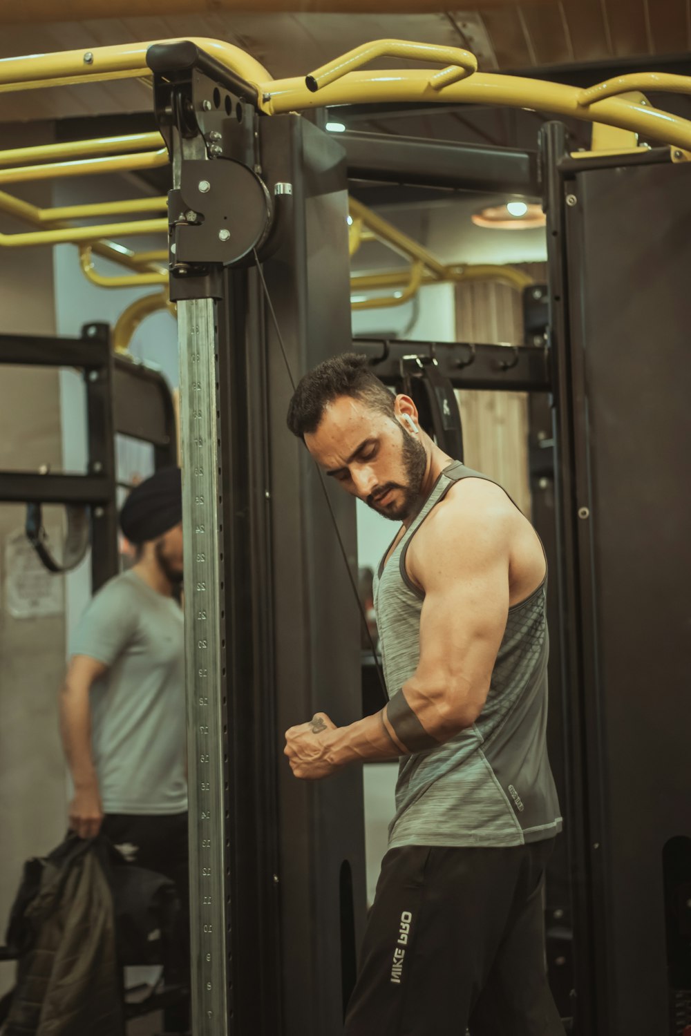 man in gray tank top standing near black metal frame