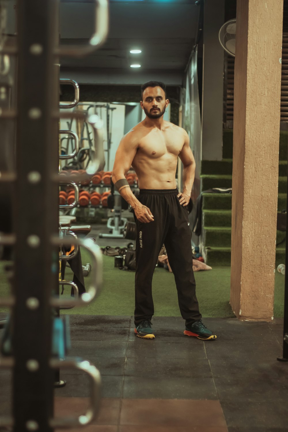 topless man in black pants and blue and red sneakers standing on blue and white basketball