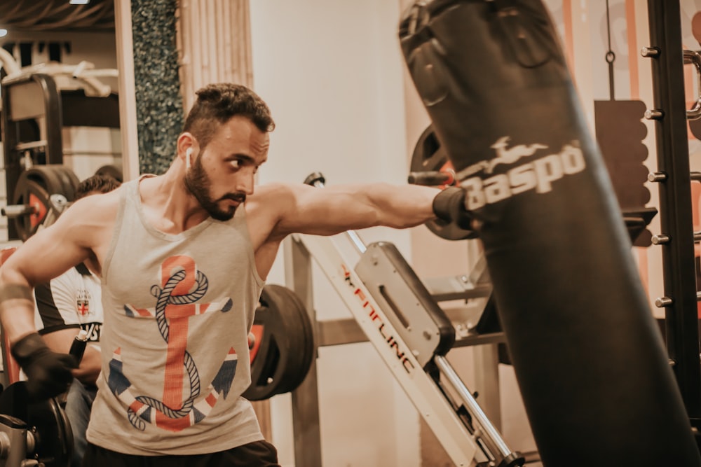 man in gray and orange crew neck t-shirt using black and white exercise equipment