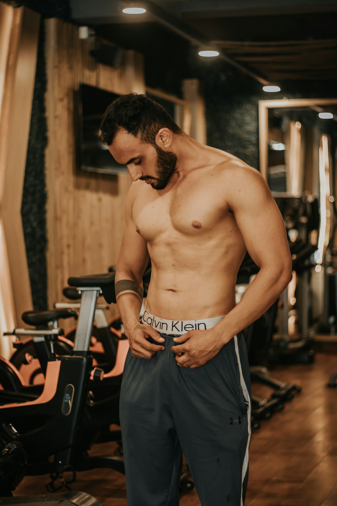 topless man in black pants standing near exercise equipments