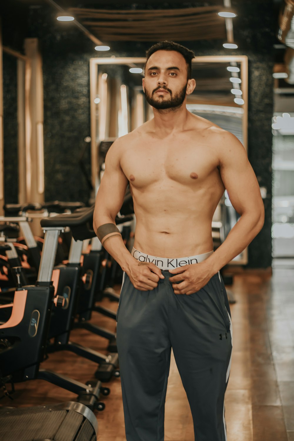 homme aux seins nus en short bleu debout sur le plancher en bois