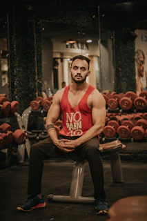 man in red tank top sitting on black chair