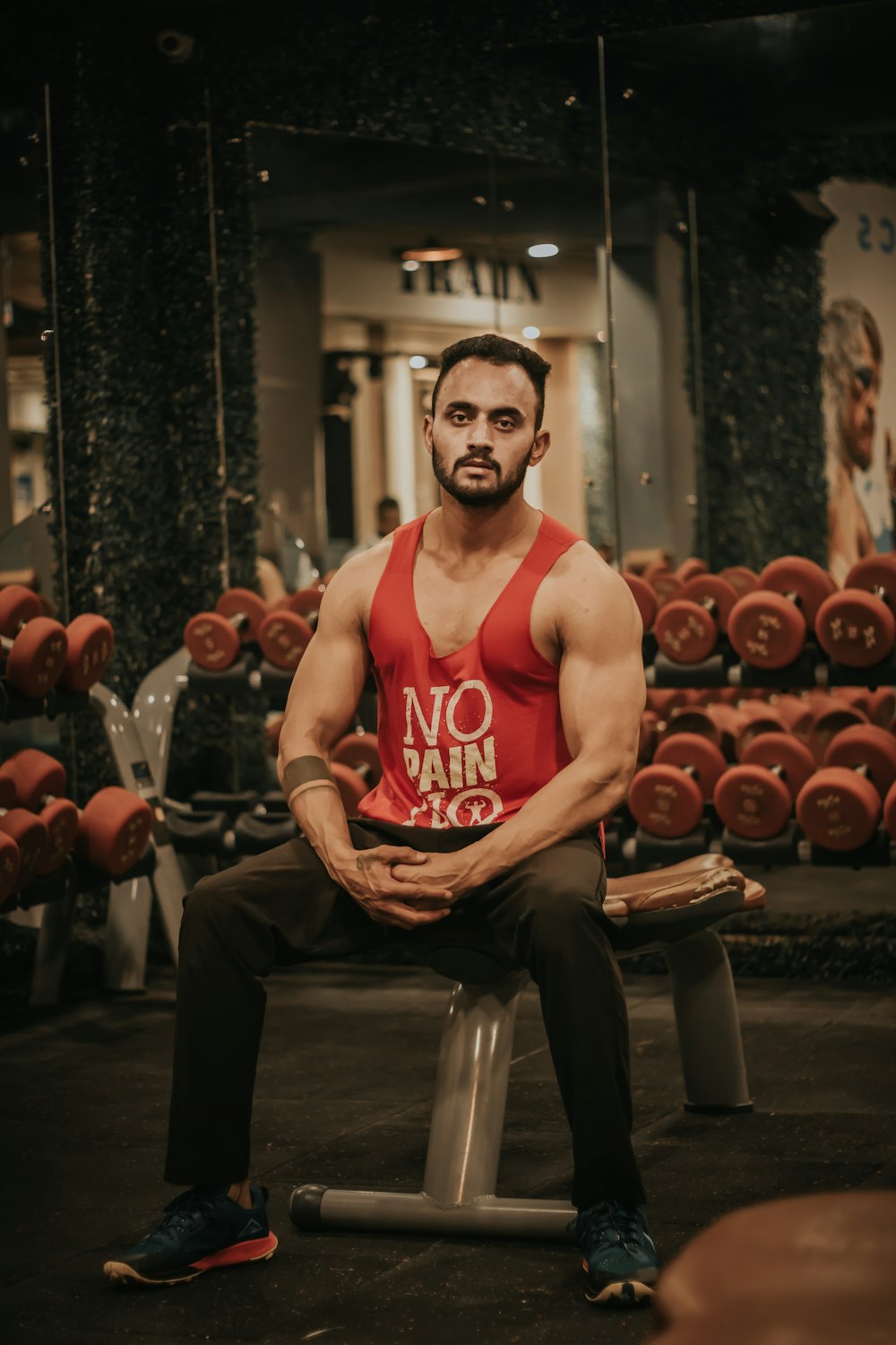 man in red tank top sitting on black chair